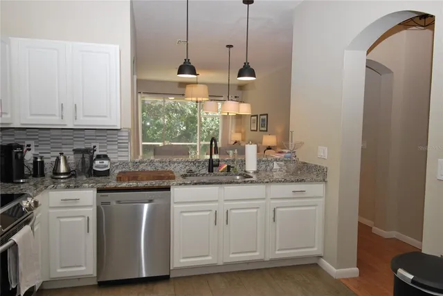 a kitchen with granite countertop a sink and white cabinets