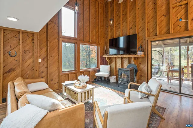 a living room with furniture a flat screen tv and a floor to ceiling window
