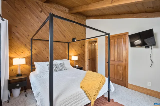 a bedroom with a bed and a flat tv screen on the dresser