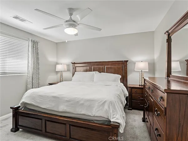 a bedroom with a bed and a lamp on the dresser