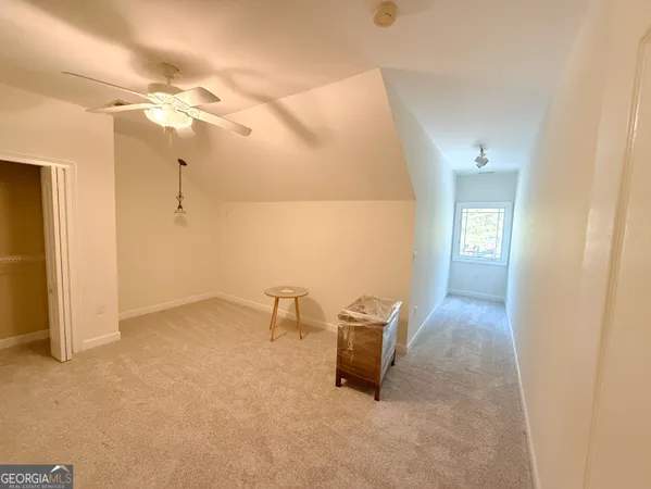 an empty room with chandelier fan and windows