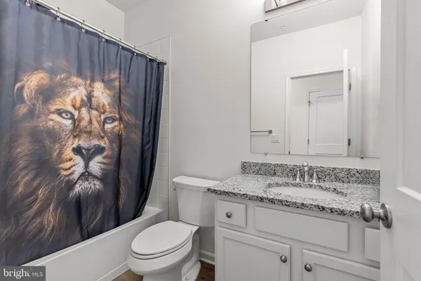 a bathroom with a granite countertop sink a toilet and a shower curtain