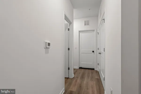 a view of a hallway with wooden floor and a bathroom
