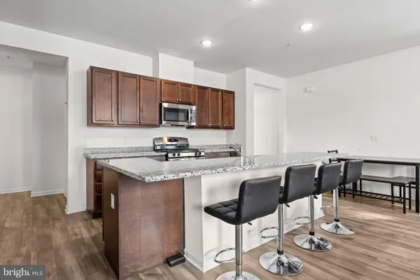 a kitchen with stainless steel appliances granite countertop a stove a sink a microwave a refrigerator and chairs