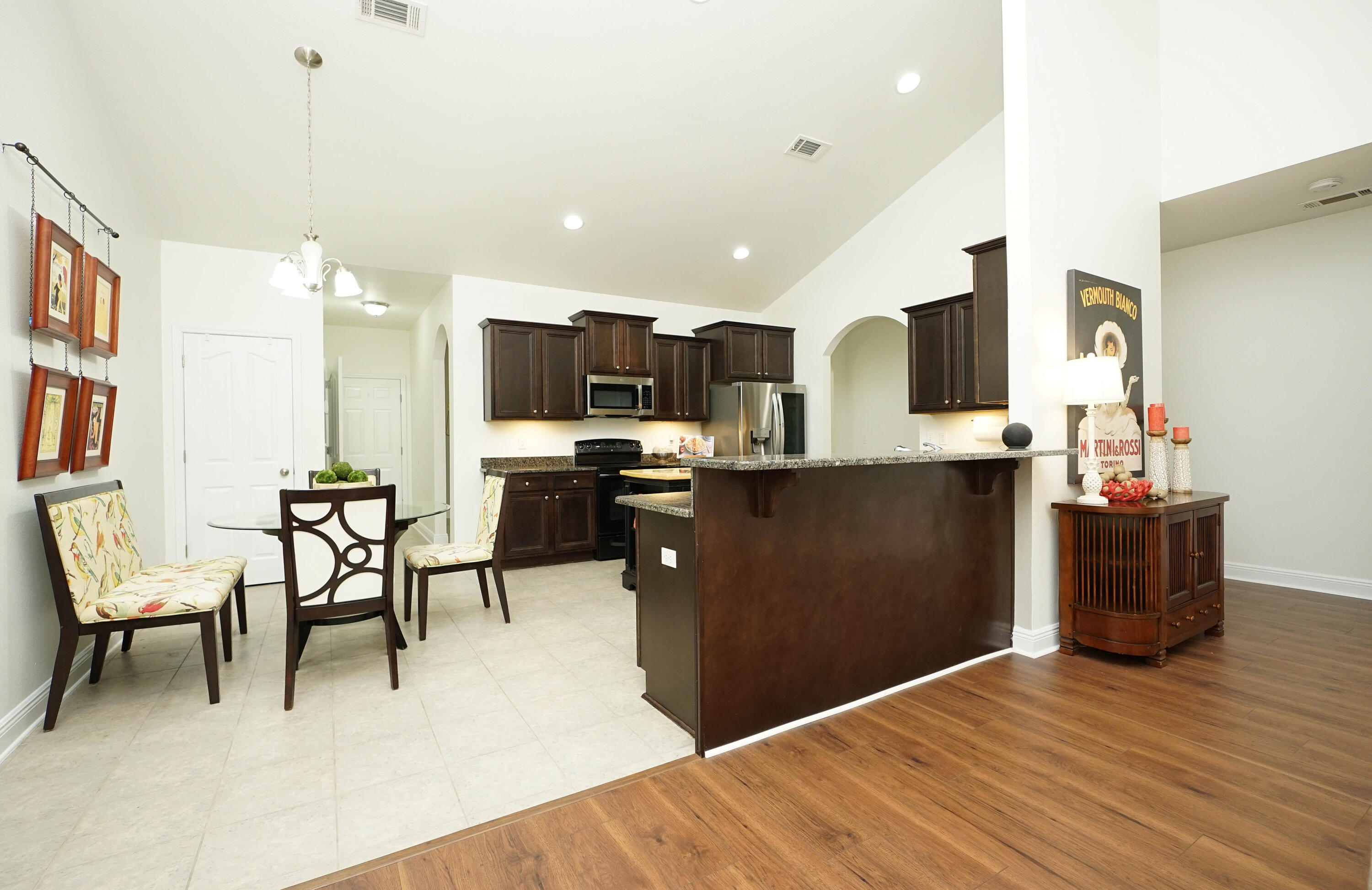 614 Red Fern Road Crestview, FL 32536 - Photo 12 of 43 a kitchen with stainless steel appliances kitchen island granite countertop a refrigerator a stove a sink a dining table and chairs with wooden floor