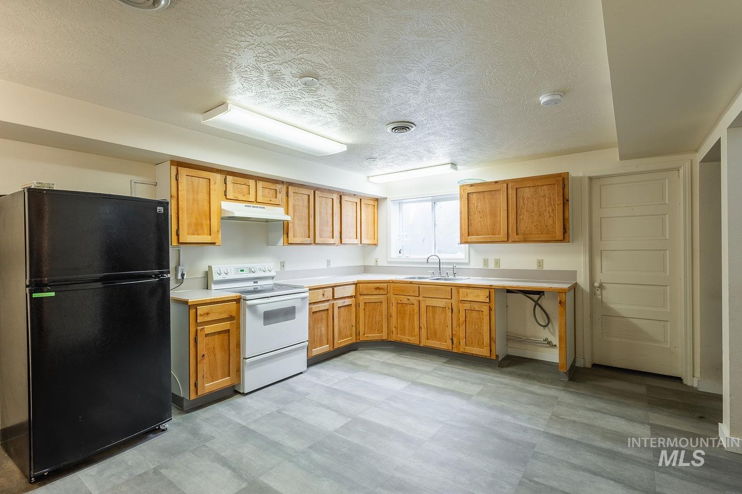 6050 Elmore Road Fruitland, ID 83619 - Photo 28 of 48 Kitchen with freestanding refrigerator, a textured ceiling, electric stove, light floors, and light countertops