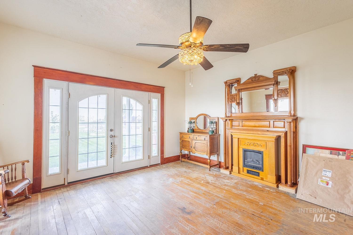 6050 Elmore Road Fruitland, ID 83619 - Photo 5 of 48 Living room featuring french doors, hardwood / wood-style floors, a glass covered fireplace, ceiling fan, and a textured ceiling