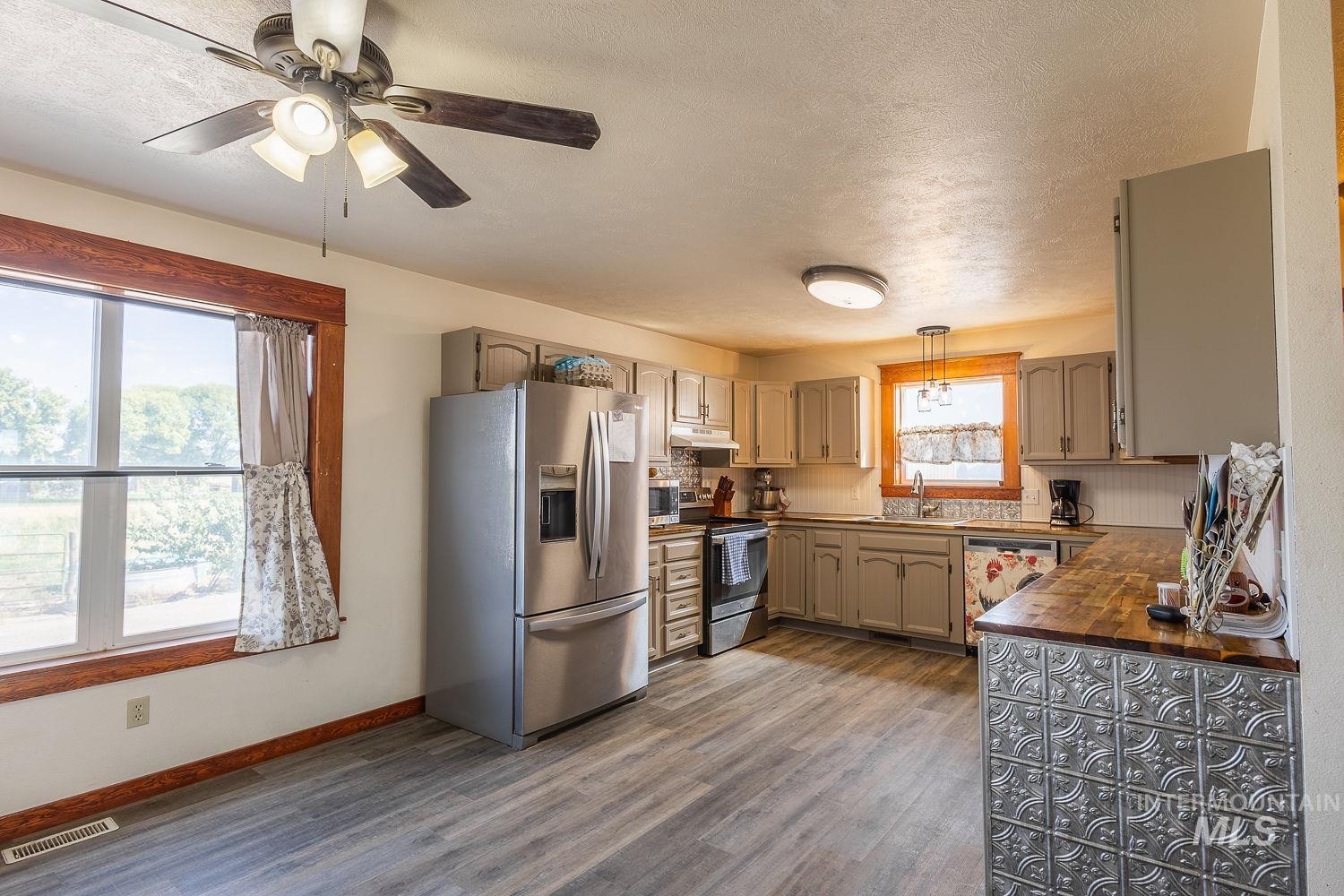6050 Elmore Road Fruitland, ID 83619 - Photo 10 of 48 Kitchen with appliances with stainless steel finishes, wooden counters, a textured ceiling, dark wood-style flooring, and backsplash