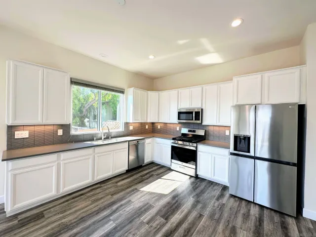 a kitchen with granite countertop stainless steel appliances a refrigerator sink and microwave