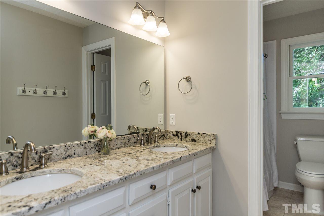 4908 Fielding Drive Raleigh, NC 27606 - Photo 20 of 25 The guest bathroom upstairs is simply stunning! The white cabinetry offers plenty of storage and look at the granite counters! Gorgeous! There are also dual sinks and the toilet and shower area is separated with a door.