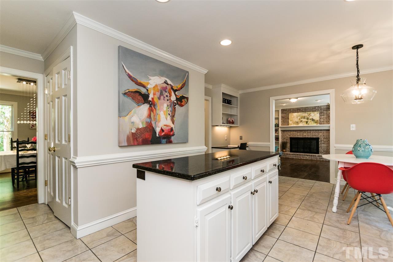 4908 Fielding Drive Raleigh, NC 27606 - Photo 8 of 25 This kitchen has a ton of storage with the center island and an extra large double door pantry. There is also a built in desk with open shelving over the top of it.