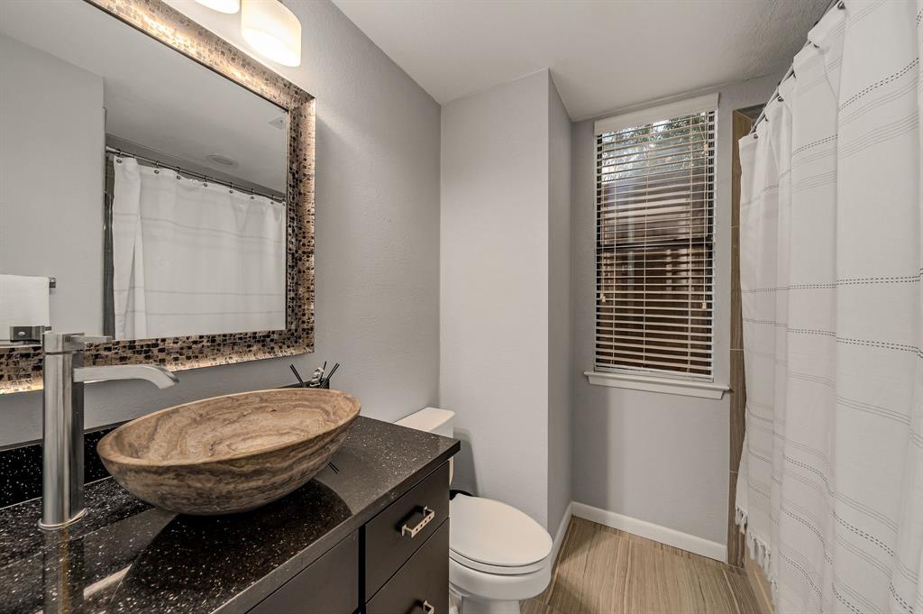 6053 Buffridge Trail Dallas, TX 75252 - Photo 16 of 40 a bathroom with a granite countertop toilet a sink and a mirror