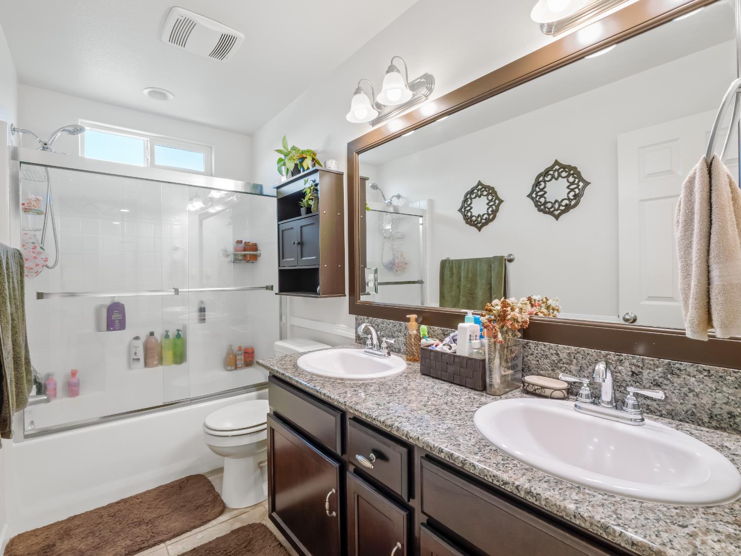3925 Griffith Avenue Clovis, CA 93619 - Photo 8 of 40 a bathroom with a granite countertop toilet sink and a large mirror