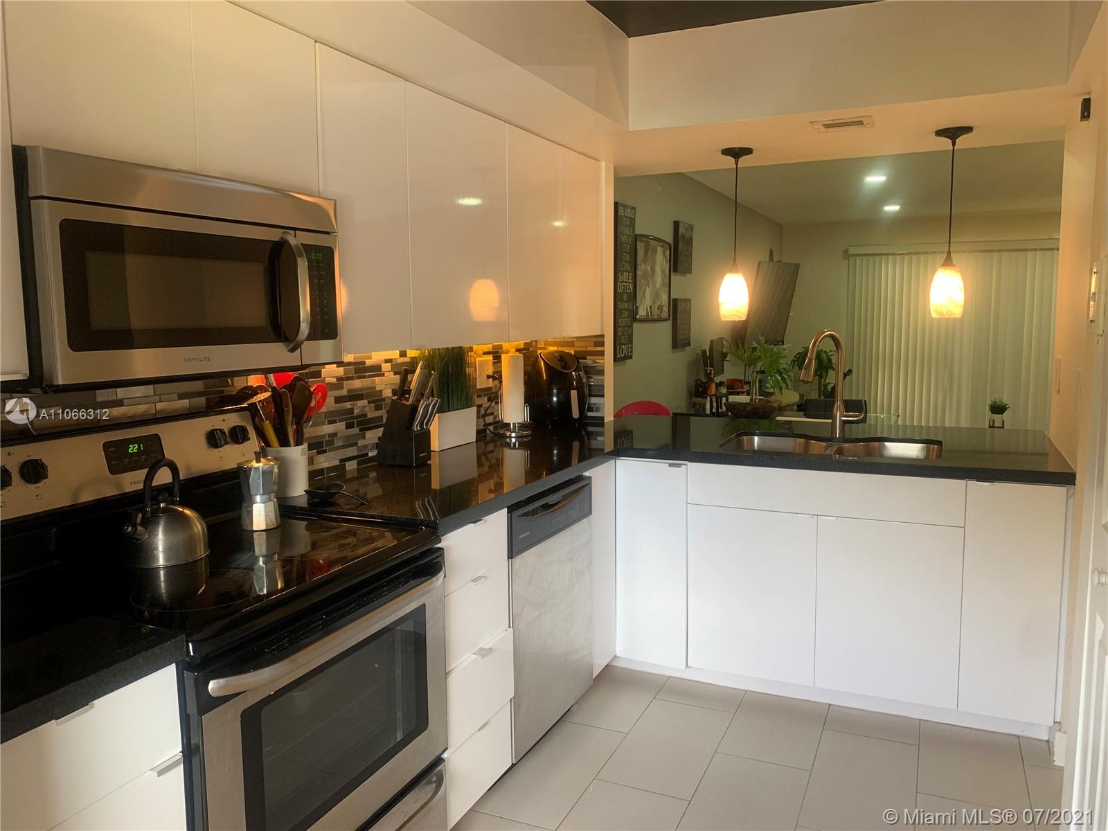 4018 Del Rio Way, Unit 4018 Sunrise, FL 33351 - Photo 21 of 94 a kitchen with stainless steel appliances kitchen island granite countertop a stove a sink and a microwave