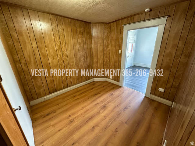 471 East 22nd Street Ogden, UT 84401 - Photo 9 of 12 Empty room featuring wood finished floors, wooden walls, a smoke detector, and a textured ceiling