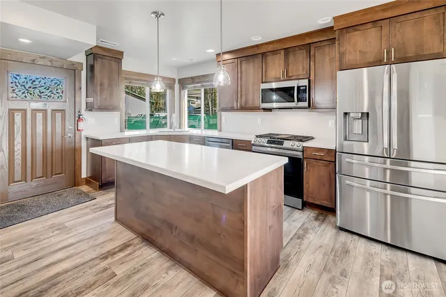 a kitchen with stainless steel appliances granite countertop a refrigerator a stove a sink and a microwave