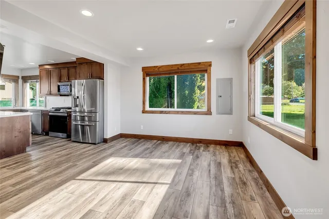 a view of a kitchen with stainless steel appliances granite countertop a stove and a wooden floors