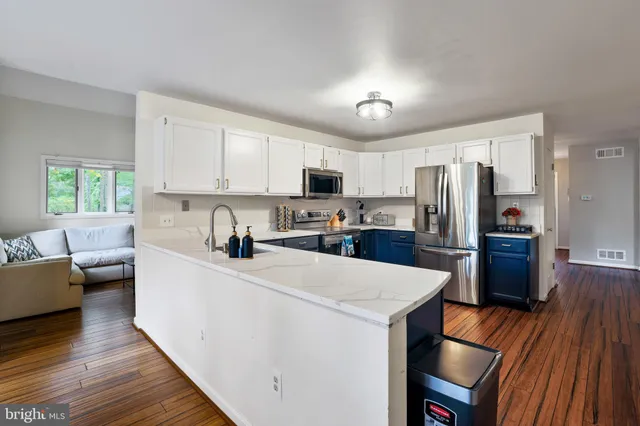 a kitchen with stainless steel appliances kitchen island granite countertop a refrigerator and a sink