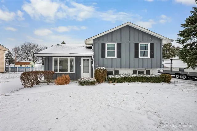 a front view of a house with a yard covered in snow