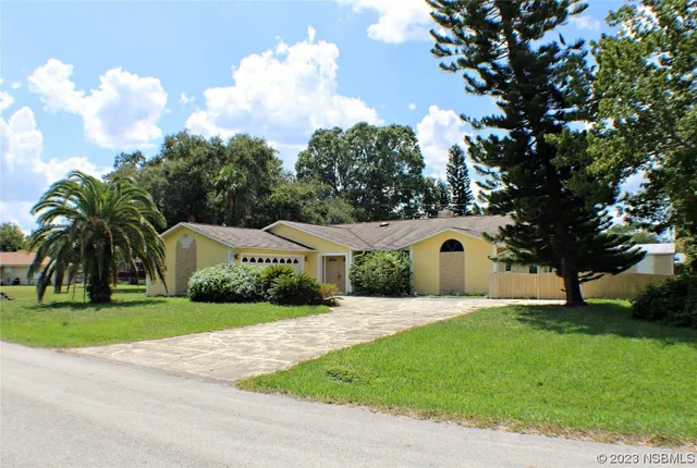 a front view of a house with a garden and trees