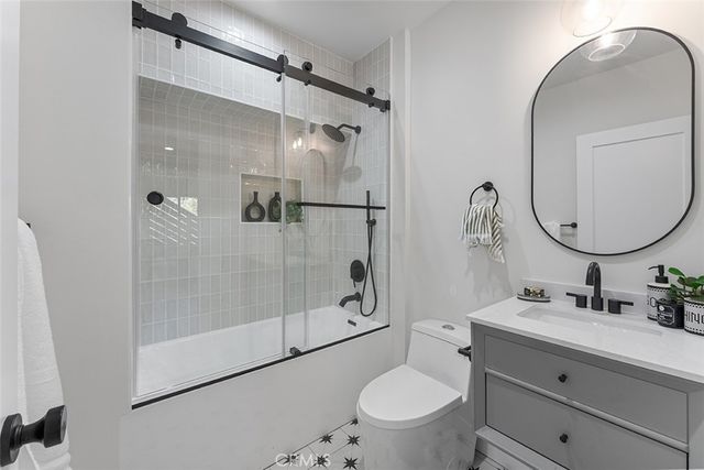 a bathroom with a granite countertop sink toilet mirror and shower