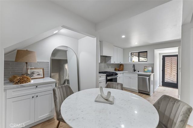 a kitchen with stainless steel appliances kitchen island granite countertop a stove a sink a refrigerator dining table and chairs