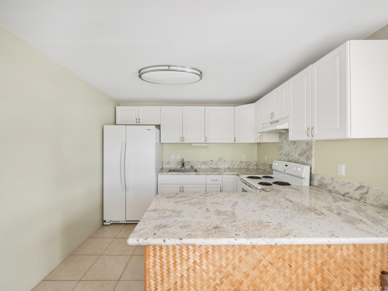 45-510 Pahia Road Kaneohe, HI 96744 - Photo 14 of 24 a kitchen with a refrigerator a stove and white cabinets