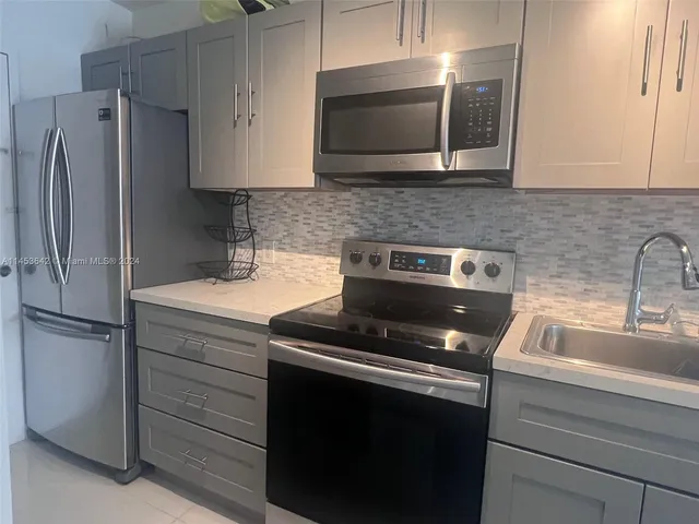 a kitchen with appliances a sink and cabinets
