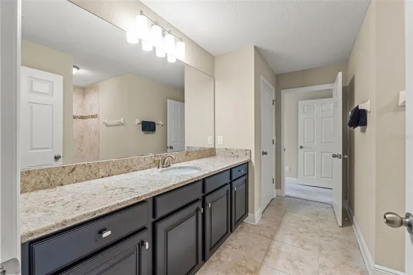 a bathroom with a granite countertop sink a mirror and a bathtub