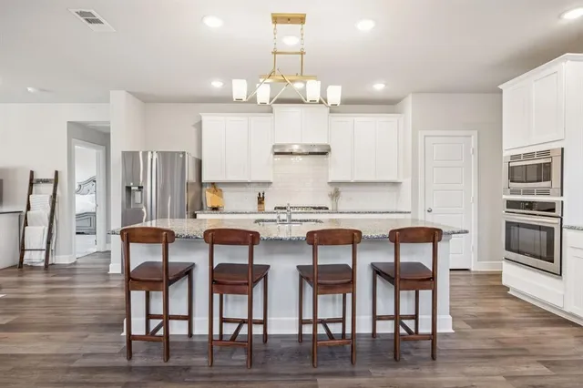 a kitchen with granite countertop a table chairs stove and cabinets