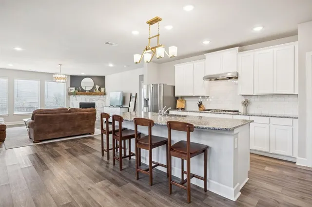 a kitchen with kitchen island granite countertop a sink and a refrigerator