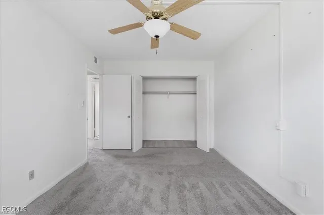 an empty room with a ceiling fan and carpet
