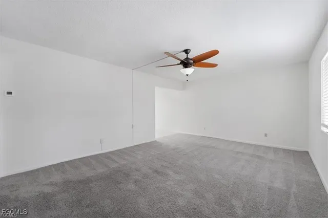 an empty room with a window and a ceiling fan