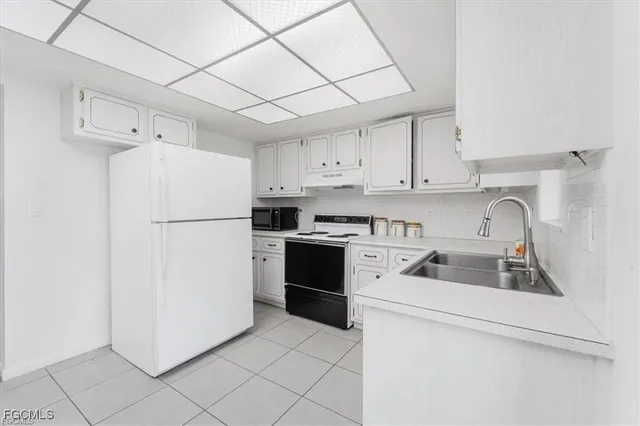 a kitchen with a refrigerator sink and cabinets