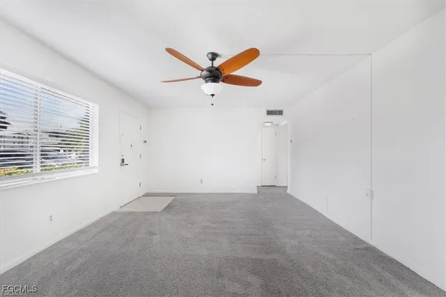 an empty room with a window and a fan
