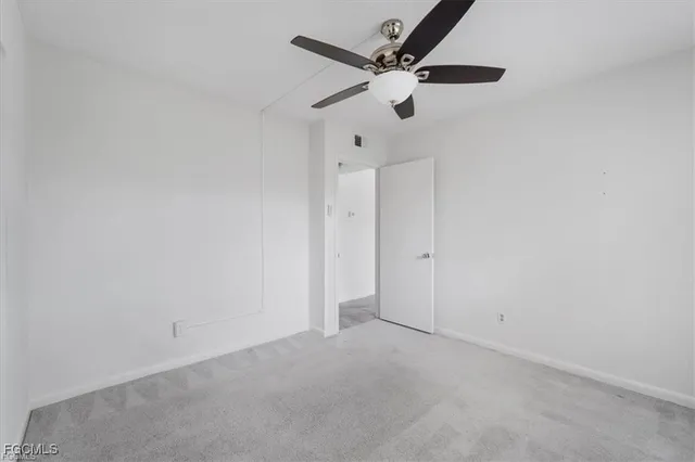 an empty room with a ceiling fan and a window
