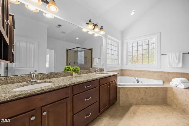 a spacious bathroom with a tub sink shower and mirror
