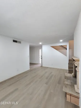 a view of an empty room with wooden floor and stairs