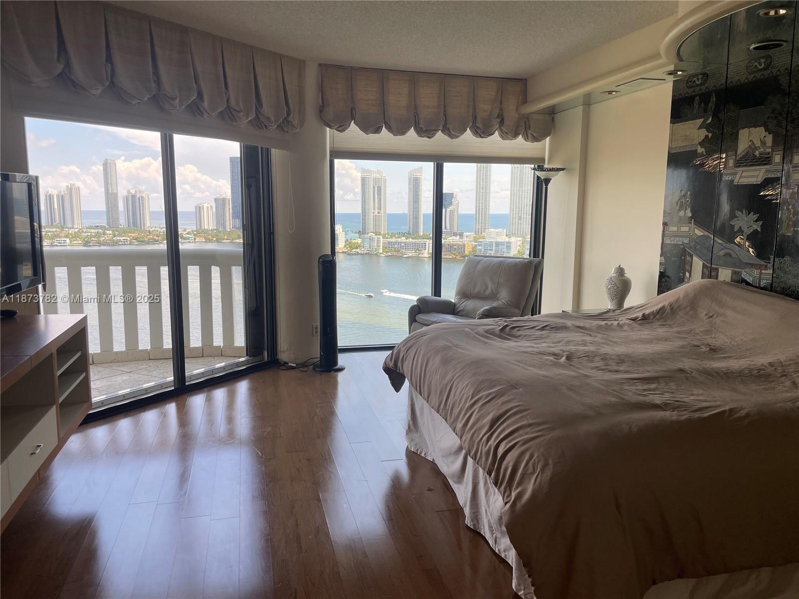 3000 Island Boulevard, Unit 2405 Aventura, FL 33160 - Photo 12 of 26 a bed sitting in a bedroom next to a large window