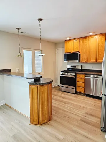 a kitchen with stainless steel appliances granite countertop a stove a sink and a wooden floors