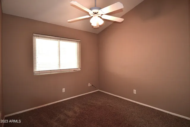 an empty room with a window and a fan