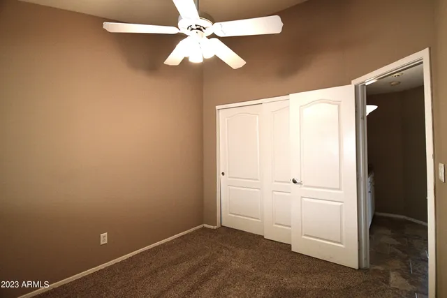 an empty room with closet and a chandelier fan