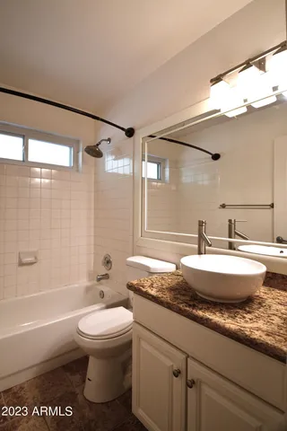 a bathroom with a granite countertop sink toilet a mirror and bathtub