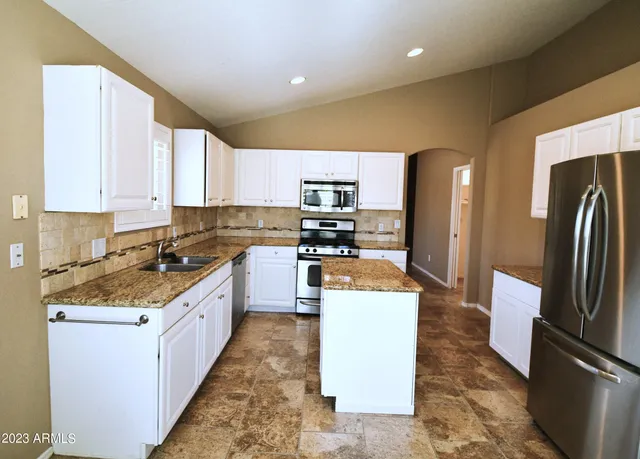 a kitchen with stainless steel appliances granite countertop a refrigerator a stove a sink and a microwave