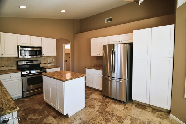 a kitchen with stainless steel appliances granite countertop a refrigerator and a stove top oven