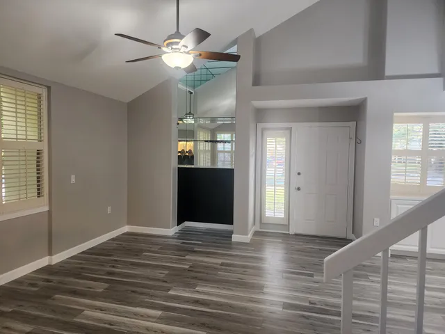 a view of an empty room with window and wooden floor