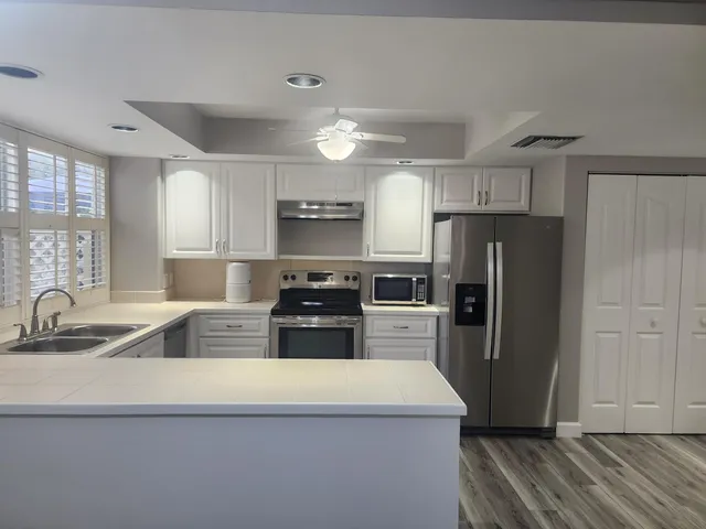 a kitchen with stainless steel appliances a refrigerator sink and microwave