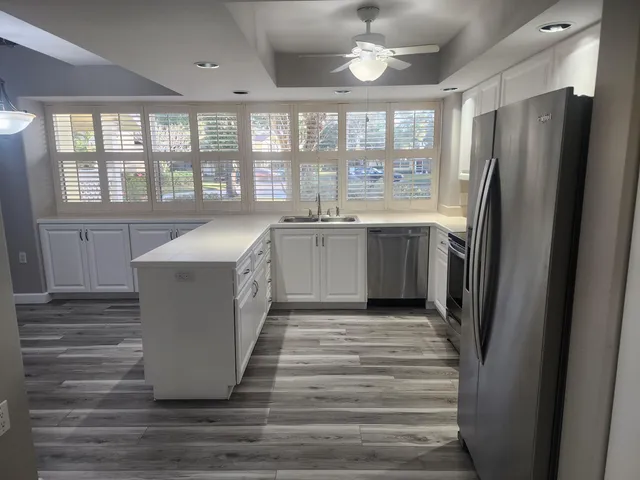 a large kitchen with kitchen island a large window a refrigerator and stainless steel appliances