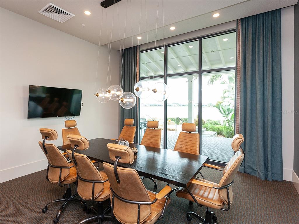 8043 Waterbend Trail Sarasota, FL 34240 - Photo 71 of 83 a dining room with furniture a flat screen tv and a floor to ceiling window