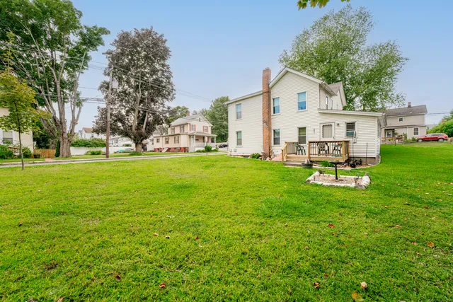 a view of a white house with a big yard and large trees